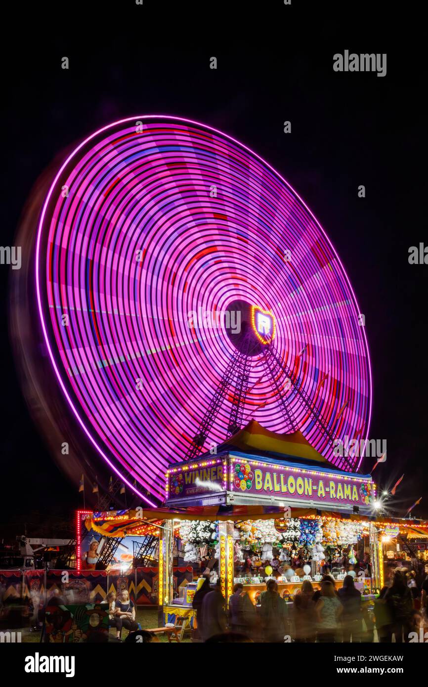 Roue hollandaise. Grande roue. Carnaval avec flou de mouvement à longue exposition. Tente de jeu de carnaval Balloon-A-Rama au premier plan. Foire de Canfield, Mahoning Coun Banque D'Images