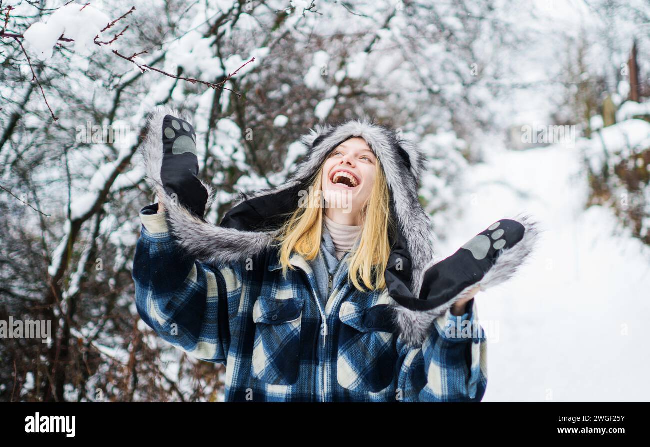 Saison hivernale. Femme heureuse en manteau à carreaux, chapeau de fourrure et moufles en hiver neigeux. Hivernal. Temps froid. Belle fille élégante marchant en hiver Banque D'Images