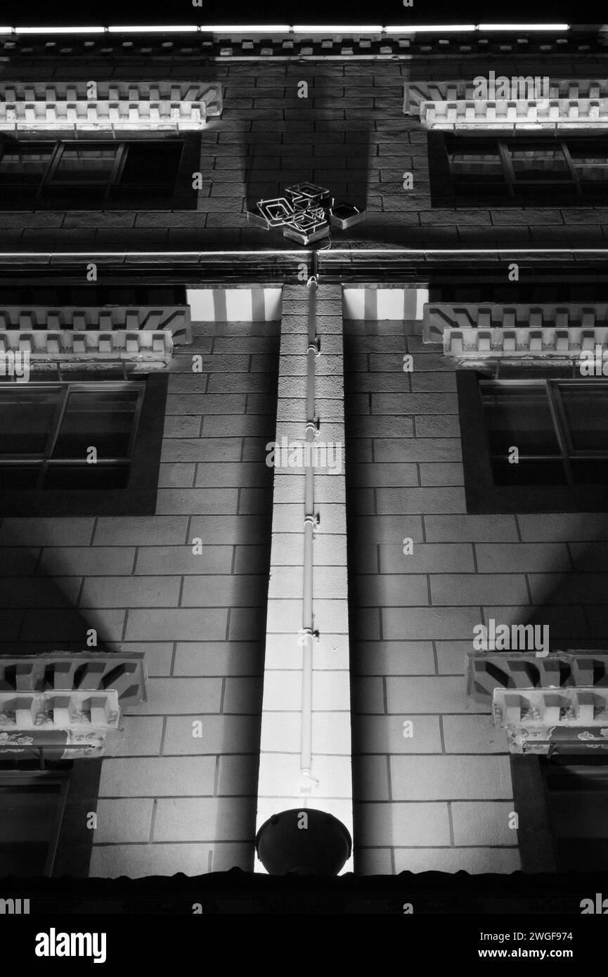 Une image en noir et blanc d'un bâtiment en briques illuminé la nuit. Banque D'Images