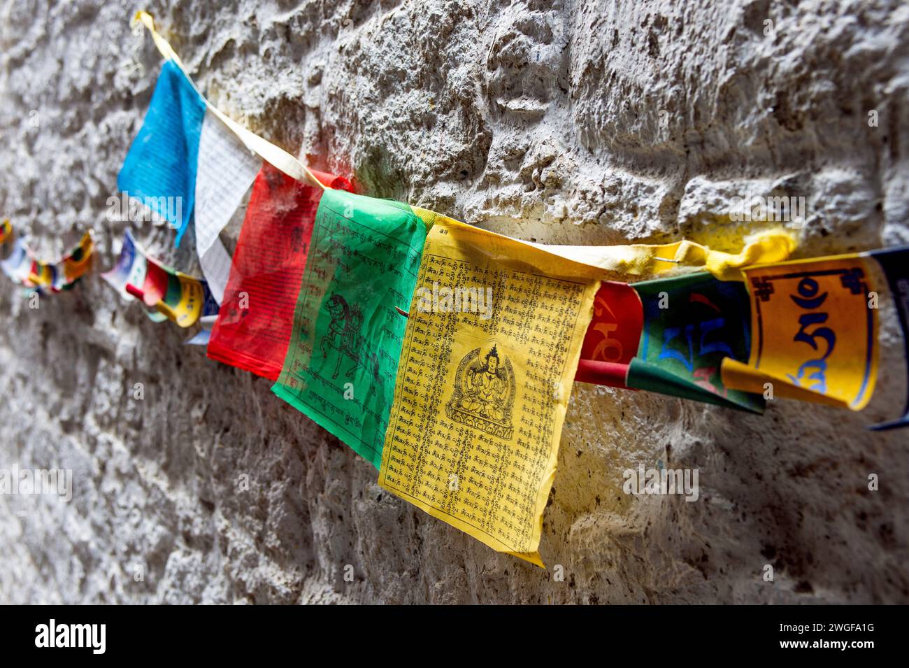 Enfilés à travers le mur de la place Barkhor à Lhassa, les drapeaux de prière tibétains sont censés répandre la bonne volonté et la compassion lorsqu'ils sont soufflés par le vent. Banque D'Images Enfilés à travers le mur de la place Barkhor à Lhassa, les drapeaux de prière tibétains sont censés répandre la bonne volonté et la compassion lorsqu'ils sont soufflés par le vent. Banque D'Images