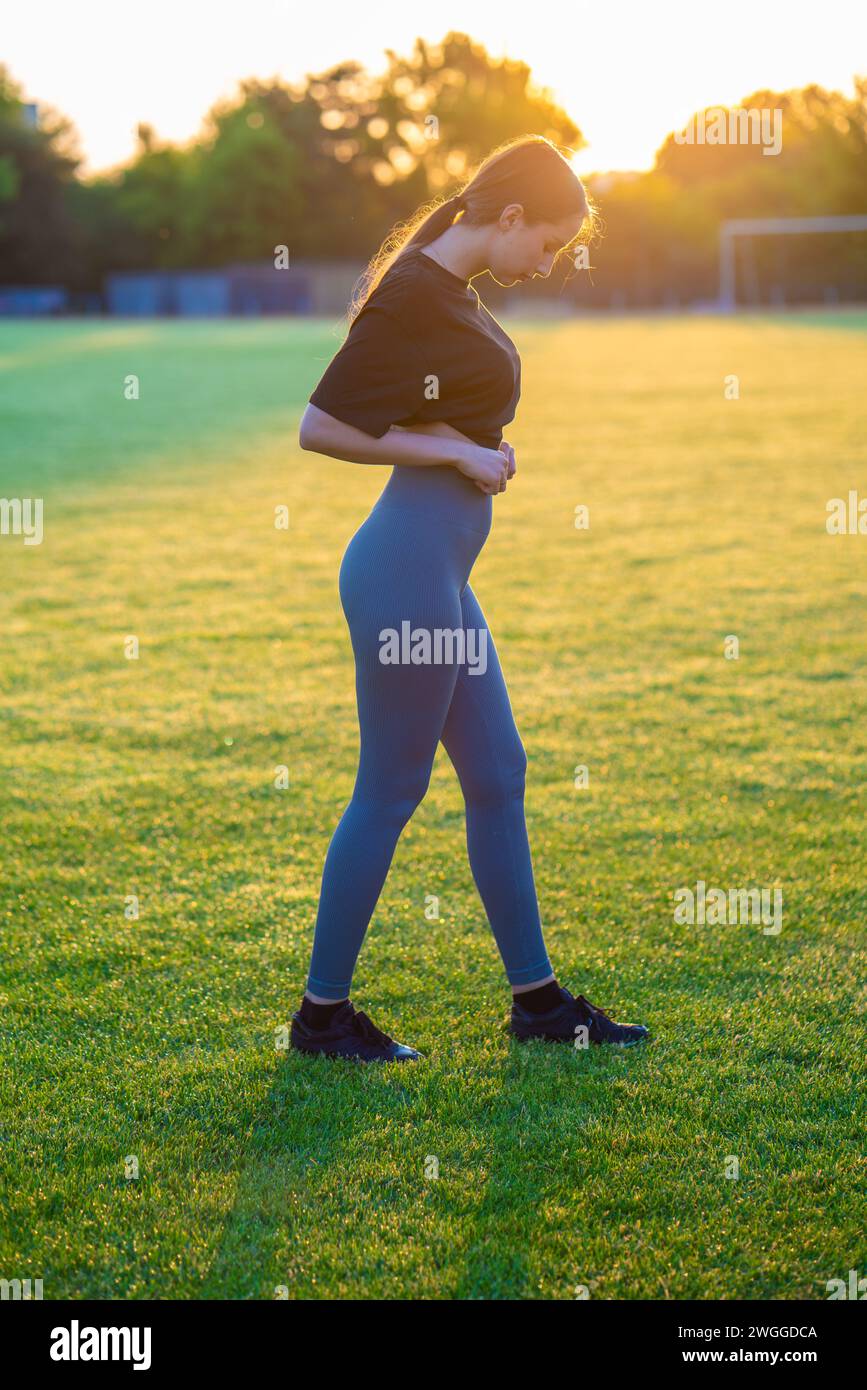 Femme silhouette debout dans le champ vert au Sunset sport Banque D'Images