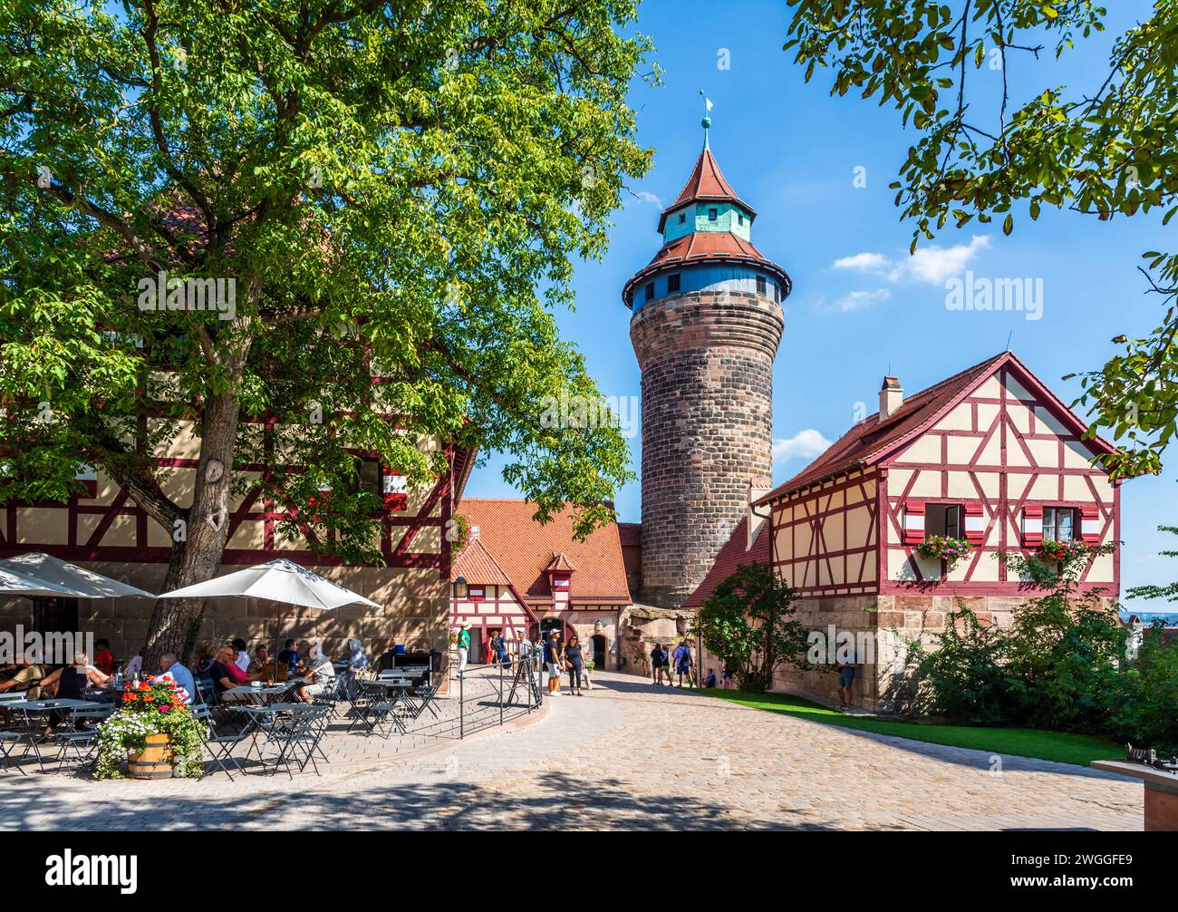 Les touristes apprécient la cour du château médiéval de Kaiserburg à Nuremberg, en Allemagne, avec le Tiefer Brunnen et le Sinwellturm. Banque D'Images