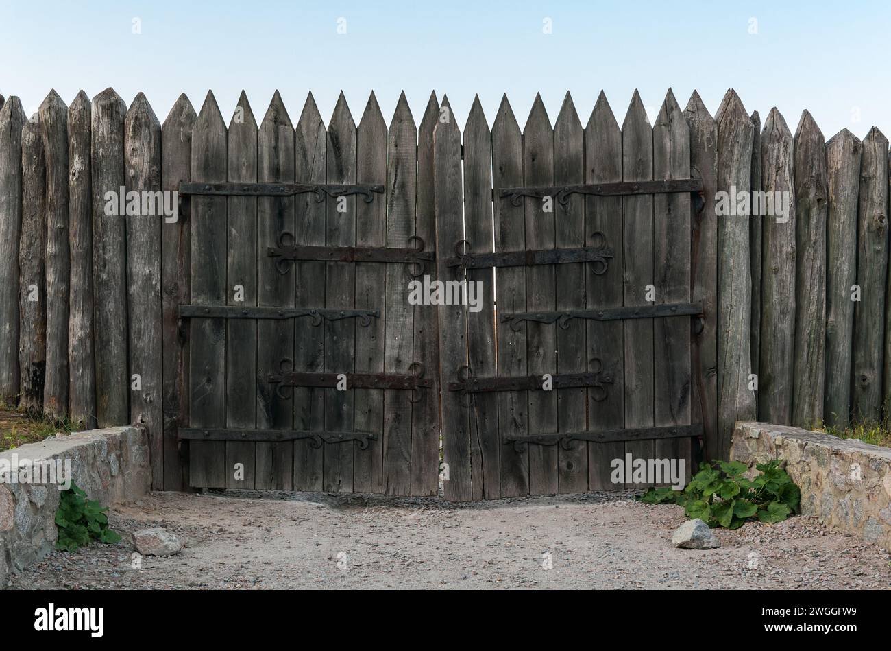 Ancienne palissade de fortification faite de bûches aiguisées et de portes en bois avec charnières forgées Banque D'Images