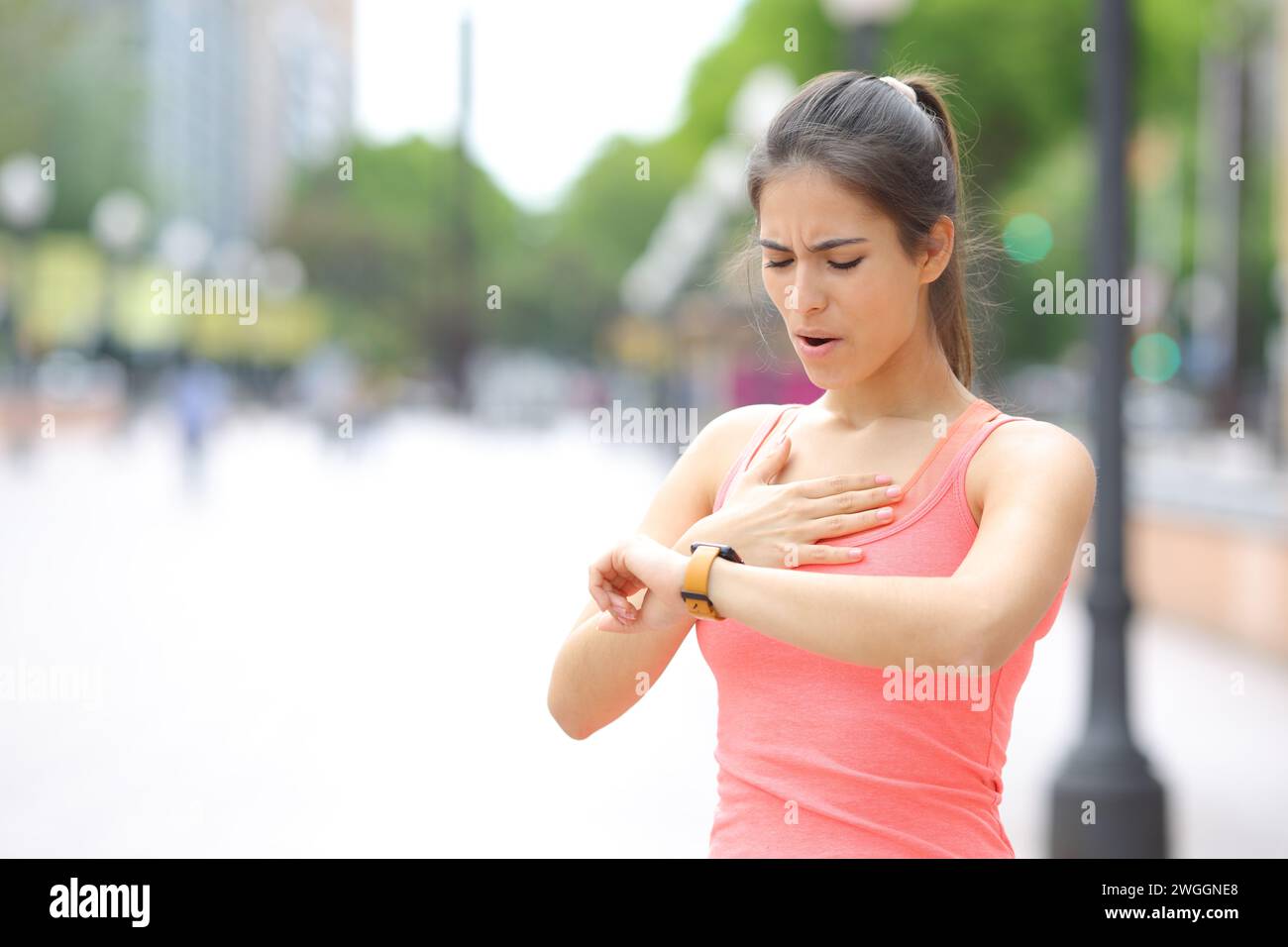 Coureur fatigué vérifiant le temps sur smartwatch après avoir couru dans la rue Banque D'Images