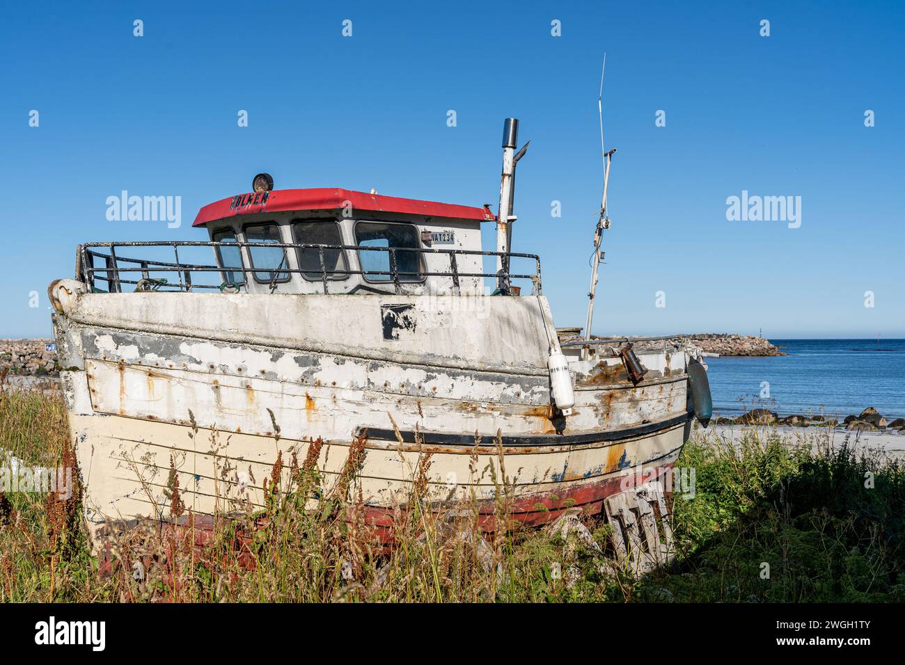 Un vieux bateau repose sur des rives sablonneuses, révélant son pont et son moteur Banque D'Images