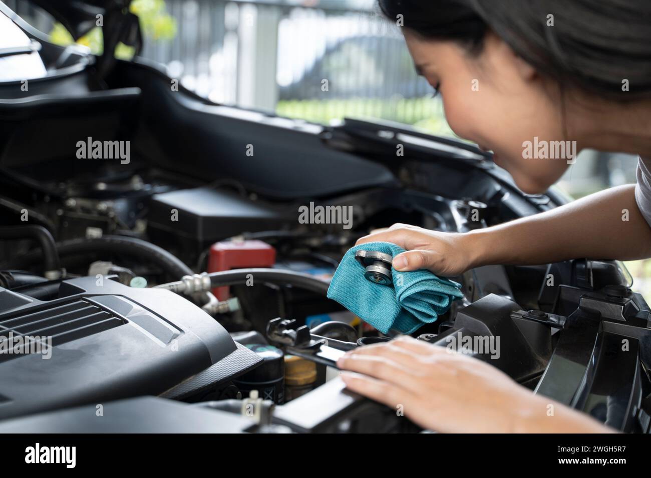 Une femme vérifie le niveau de liquide de refroidissement du moteur. Banque D'Images