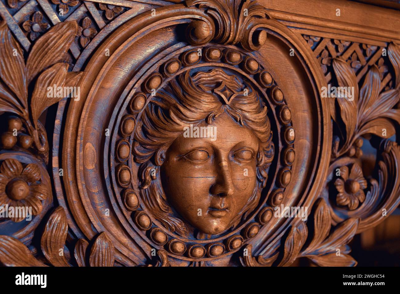 Élégante sculpture en bois du visage d'une femme (peut-être Marianne, symbole de la France) avec des motifs floraux complexes sur des meubles vintage. Paris, France. Banque D'Images