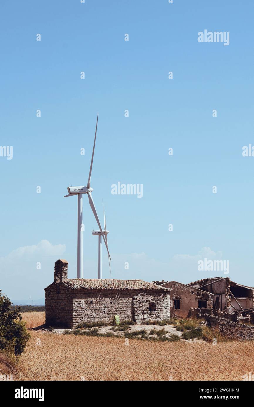 Ancienne maison détruite avec contraste de moulins à vent modernes dans la province de Conca de Barbera en Catalogne, en Espagne, le 4 juin 2023 Banque D'Images