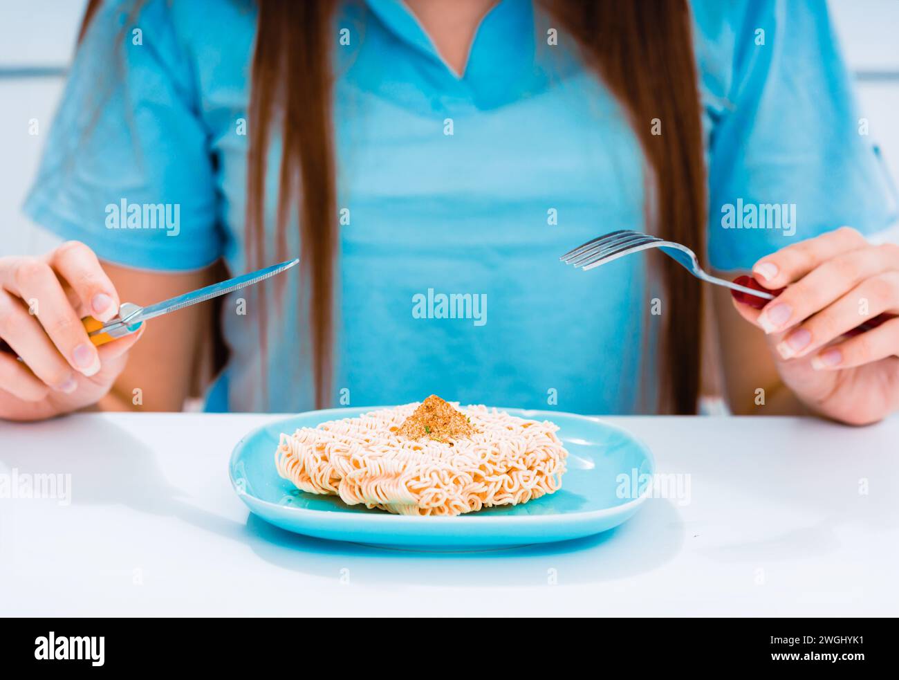femme avec cuillère et fourchette mangeant des nouilles instantanées, concept alimentaire malsain Banque D'Images