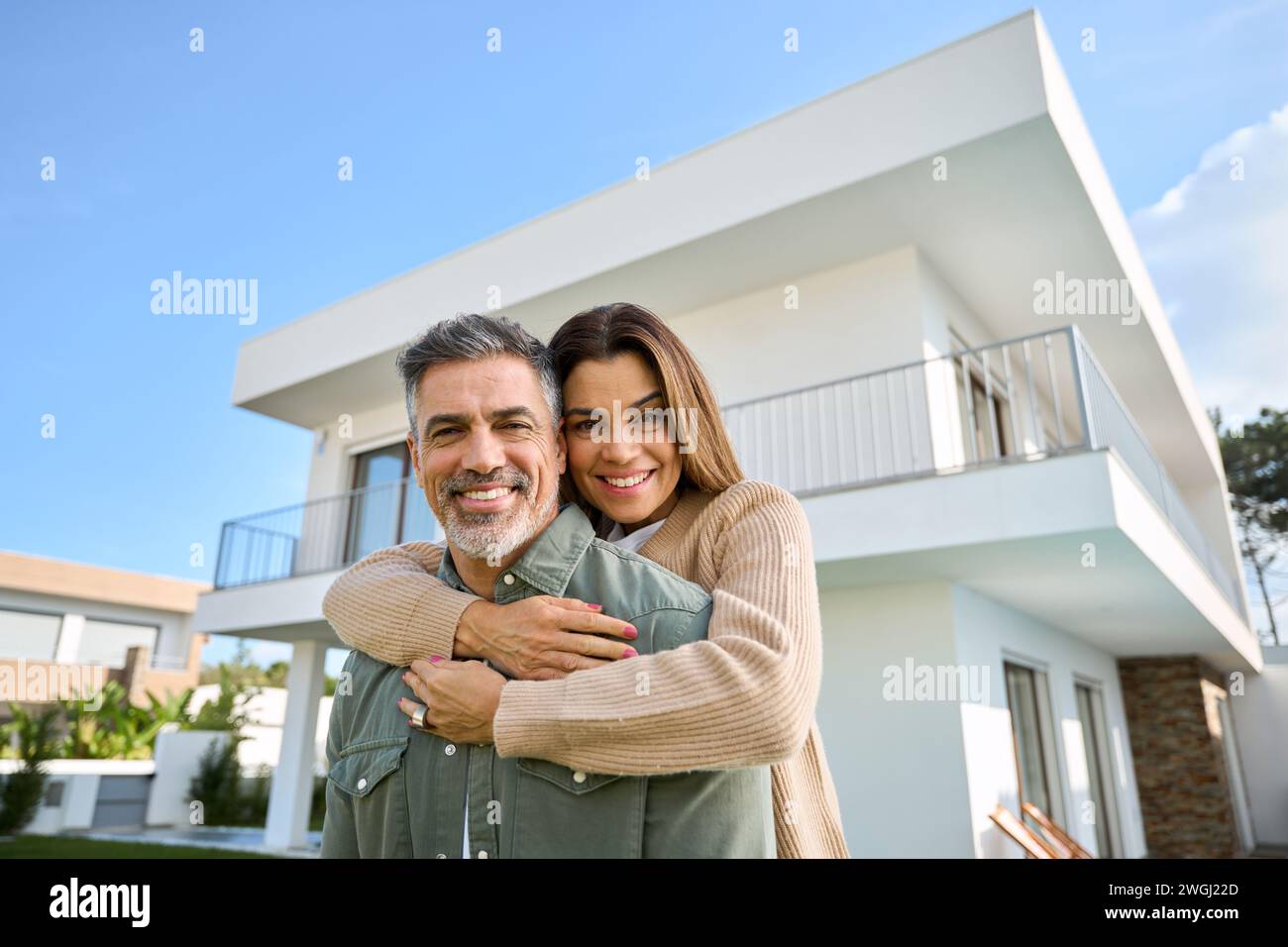 Heureux souriant famille âgée couple de nouveaux propriétaires de maison debout à l'extérieur de la maison. Banque D'Images