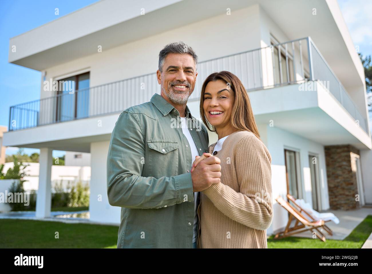 Portrait de couples familiaux matures heureux propriétaires de propriété debout à l'extérieur de la maison. Banque D'Images