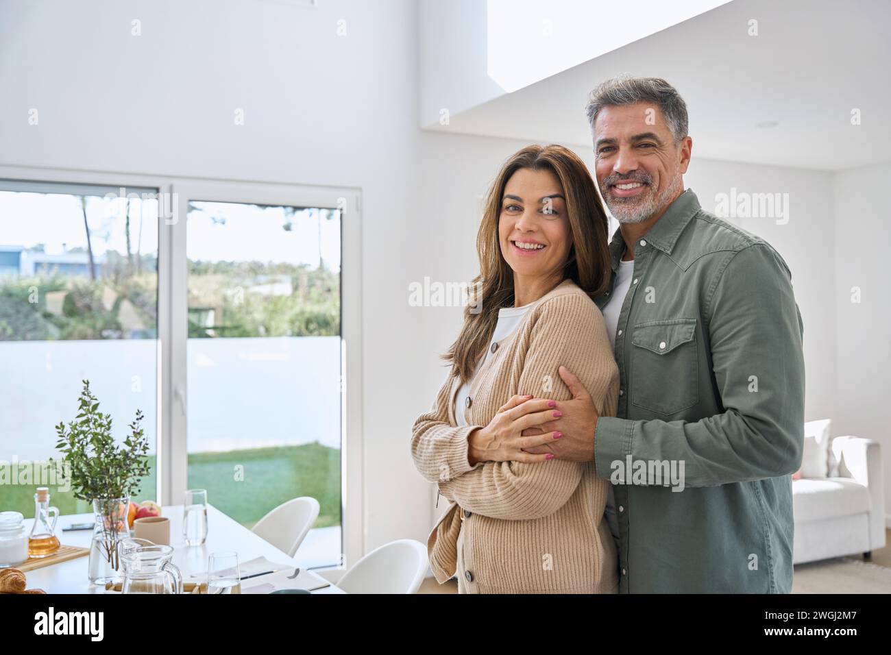 Portrait de heureux souriant couple mature propriétaires immobiliers debout à la maison. Banque D'Images