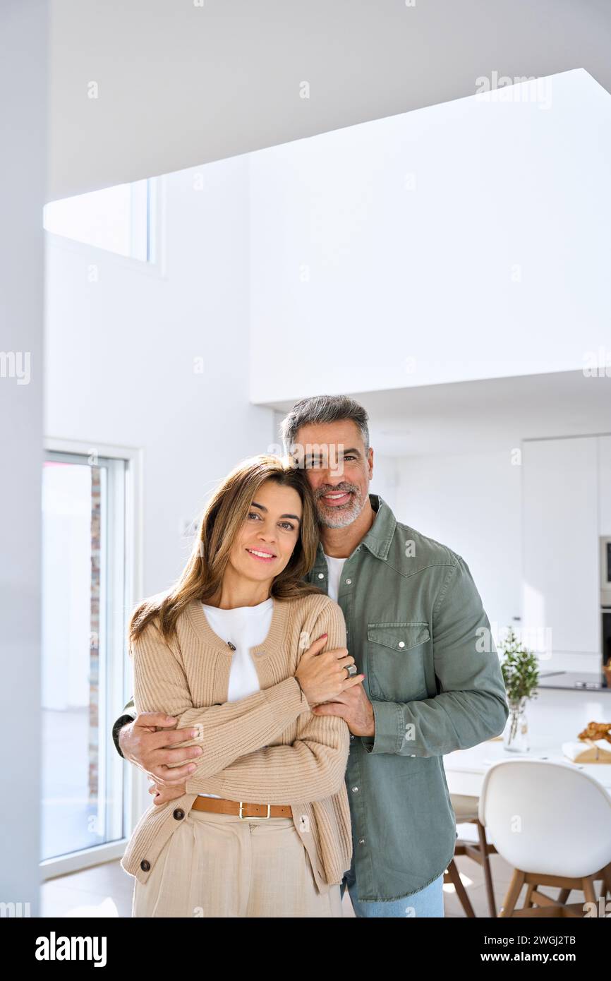 Heureux couple mature d'âge moyen serrant debout à la maison. Portrait vertical. Banque D'Images