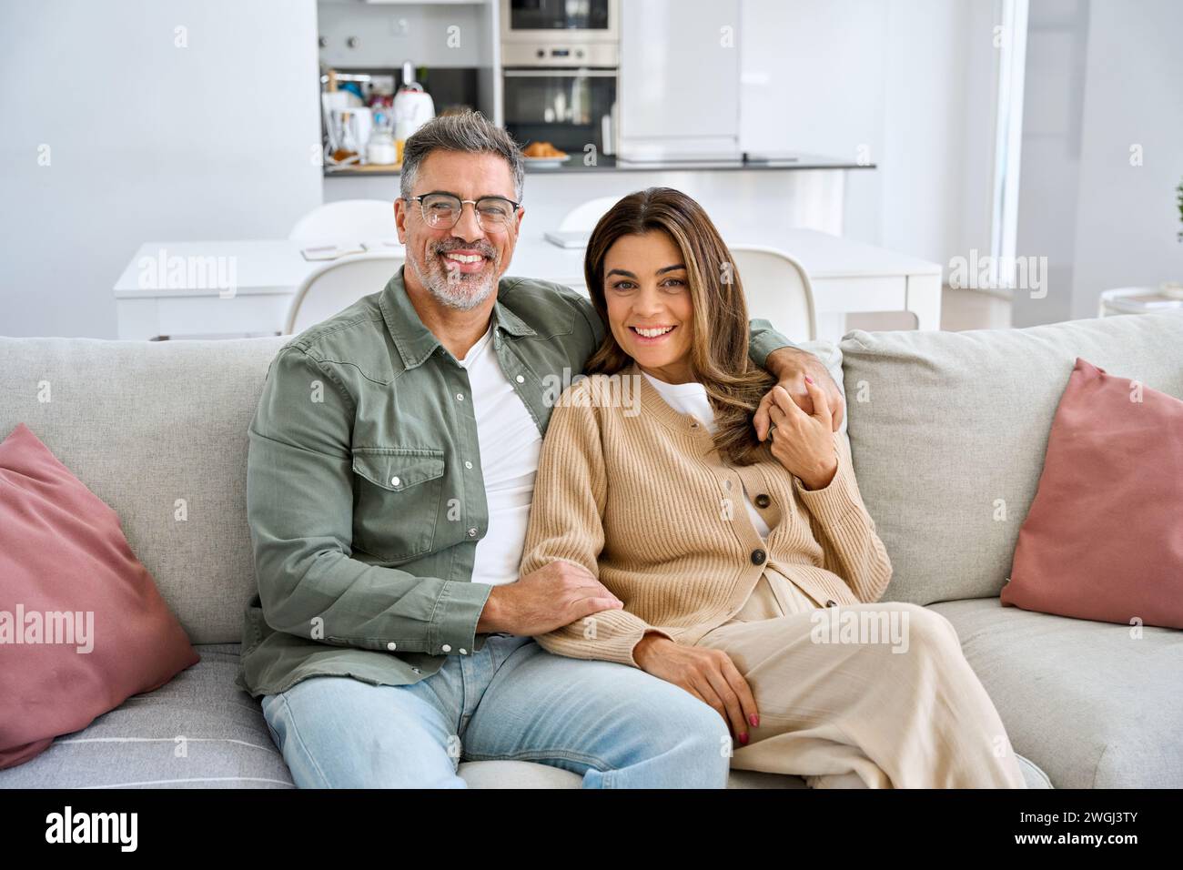 Heureux couple mature d'âge moyen embrassant assis sur le canapé à la maison. Portrait. Banque D'Images