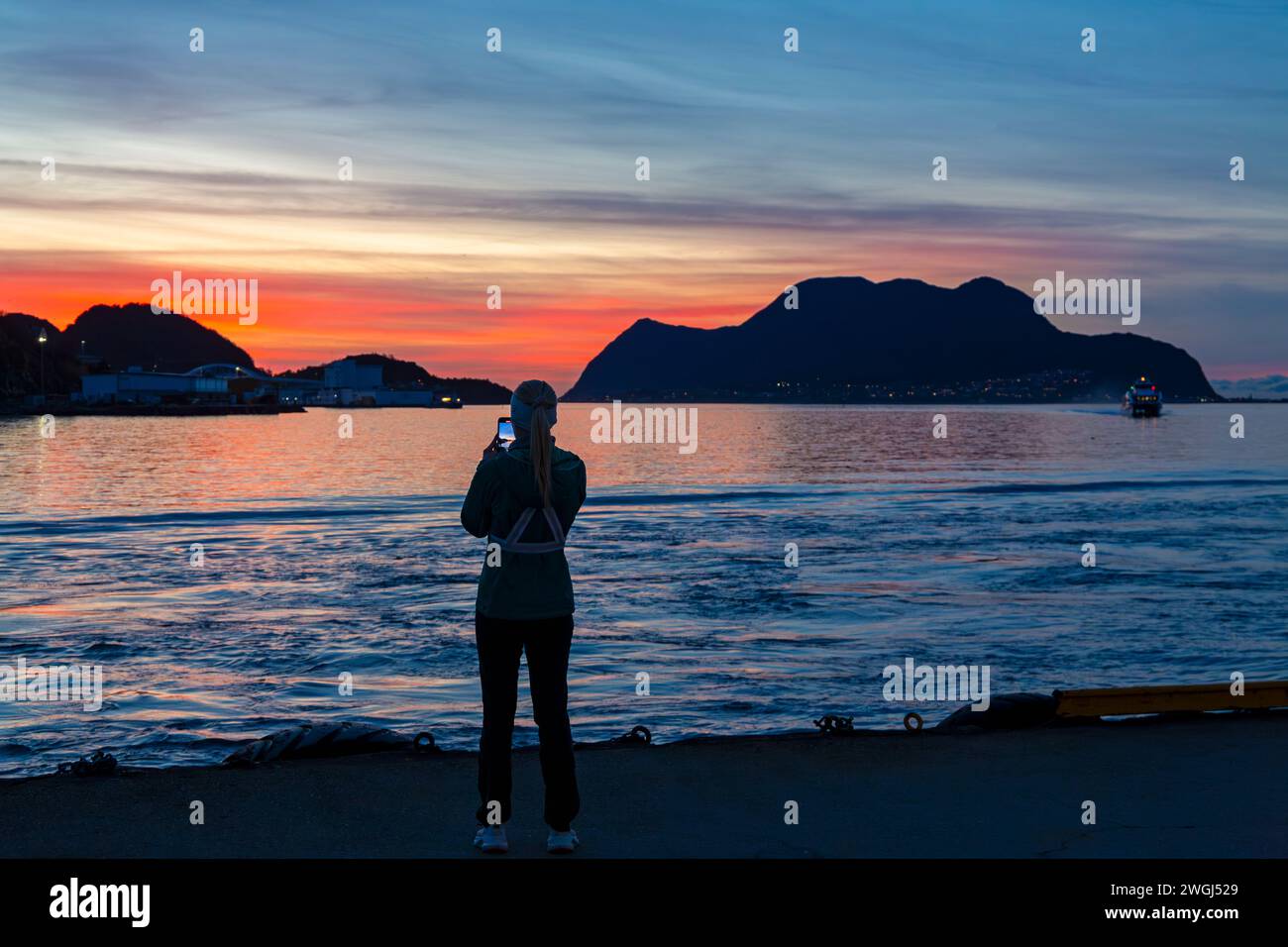 Femme prenant une photo d'un magnifique coucher de soleil à Alesund, Norvège, Scandinavie, Europe en octobre Banque D'Images
