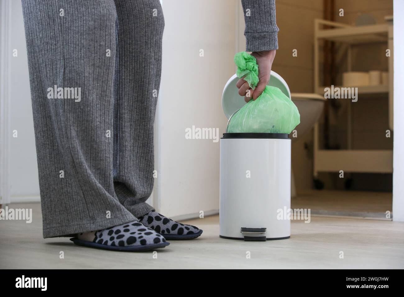 Femme au foyer jetant les ordures, prenant le sac poubelle en plastique de la poubelle dans l'appartement Banque D'Images