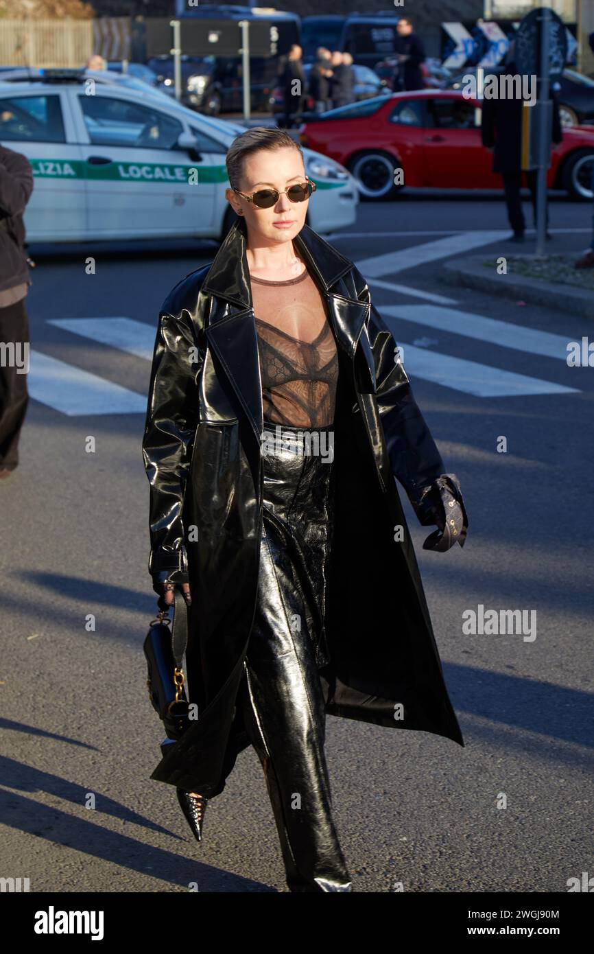 MILAN, ITALIE - 12 JANVIER 2024 : femme avec un trench en cuir noir et un pantalon avant le défilé de mode Gucci, dans le style de la semaine de la mode de Milan Banque D'Images