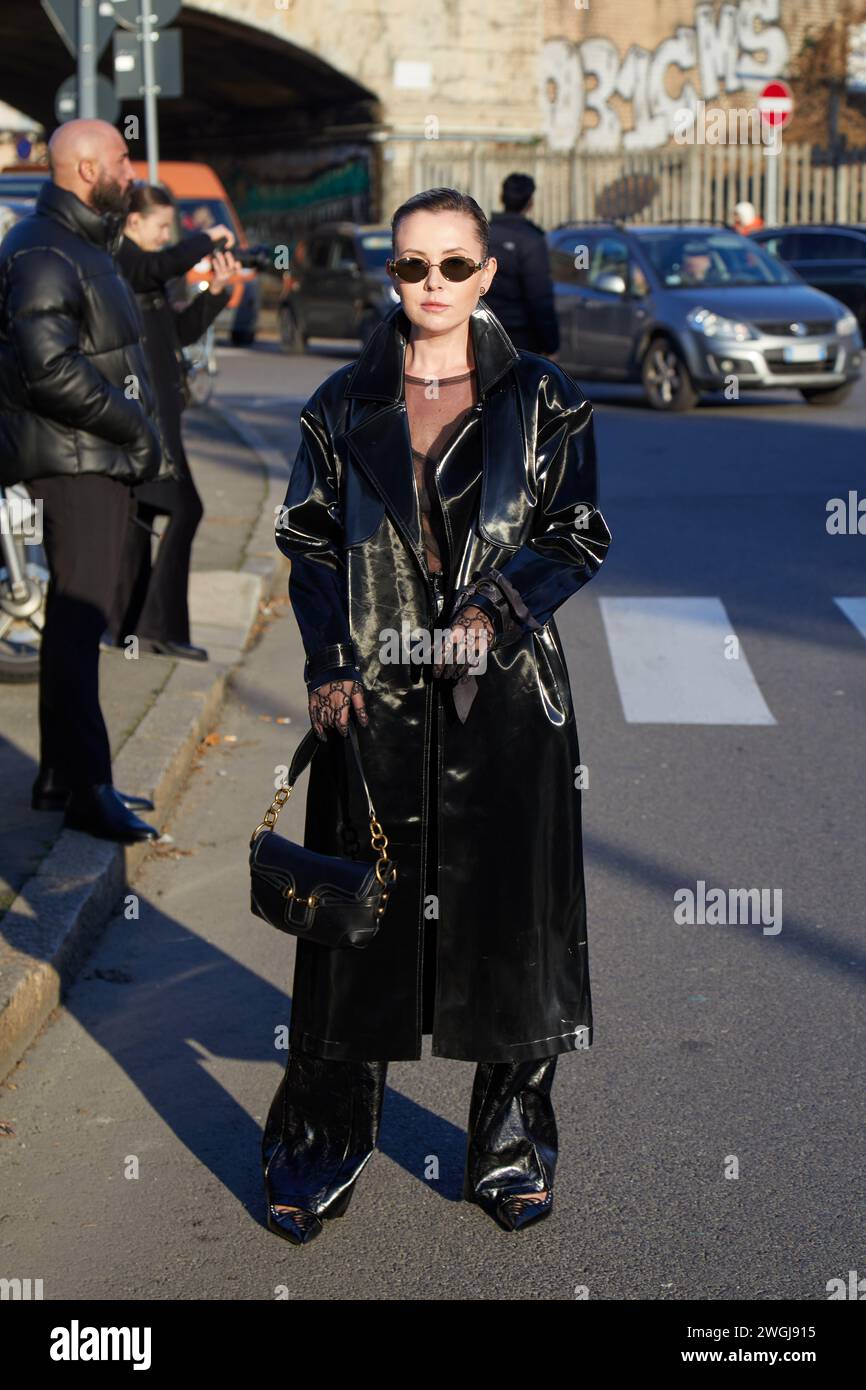 MILAN, ITALIE - 12 JANVIER 2024 : femme avec un trench en cuir noir et un pantalon avant le défilé de mode Gucci, dans le style de la semaine de la mode de Milan Banque D'Images