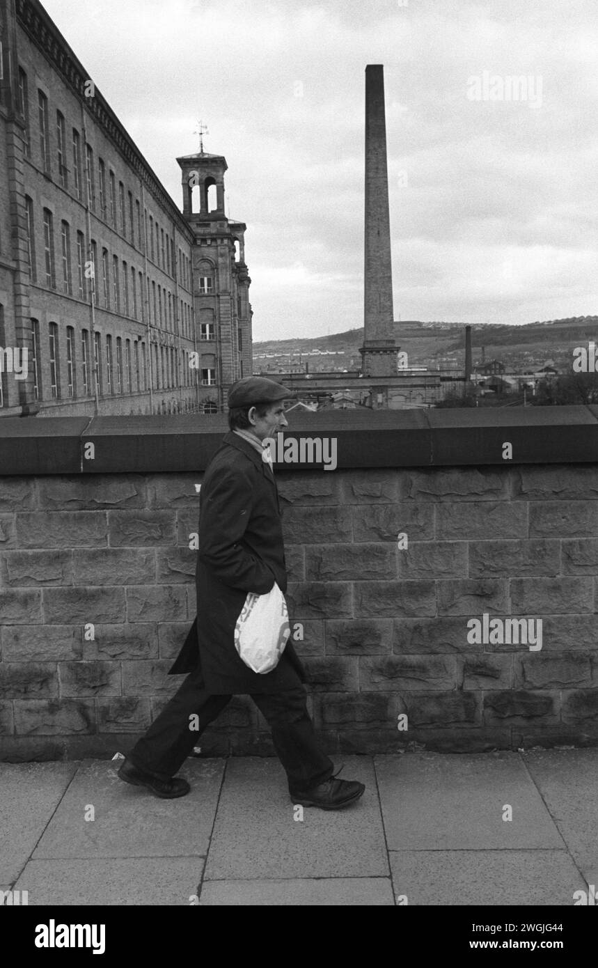 Un ouvrier d'usine rentre chez lui après une journée de travail à Salts Cotton Mill. Salts Mill nommé d'après Sir Titus Salt a été fermé en 1986 après 133 ans comme usine textile. Saltaire, Bradford. ANNÉES 1981 1980 ROYAUME-UNI HOMER SYKES Banque D'Images