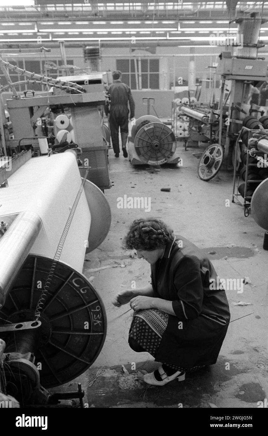 Une femme travaille en usine, travaillant dans l'industrie textile à Salts Mill, West Yorkshire. 1980s Royaume-Uni. Sa machine est tombée en panne. Salts Mill une usine de textiles de coton nommée d'après Sir Titus Salt a été fermée en 1986 après 133 ans comme usine textile. ROYAUME-UNI HOMER SYKES Banque D'Images