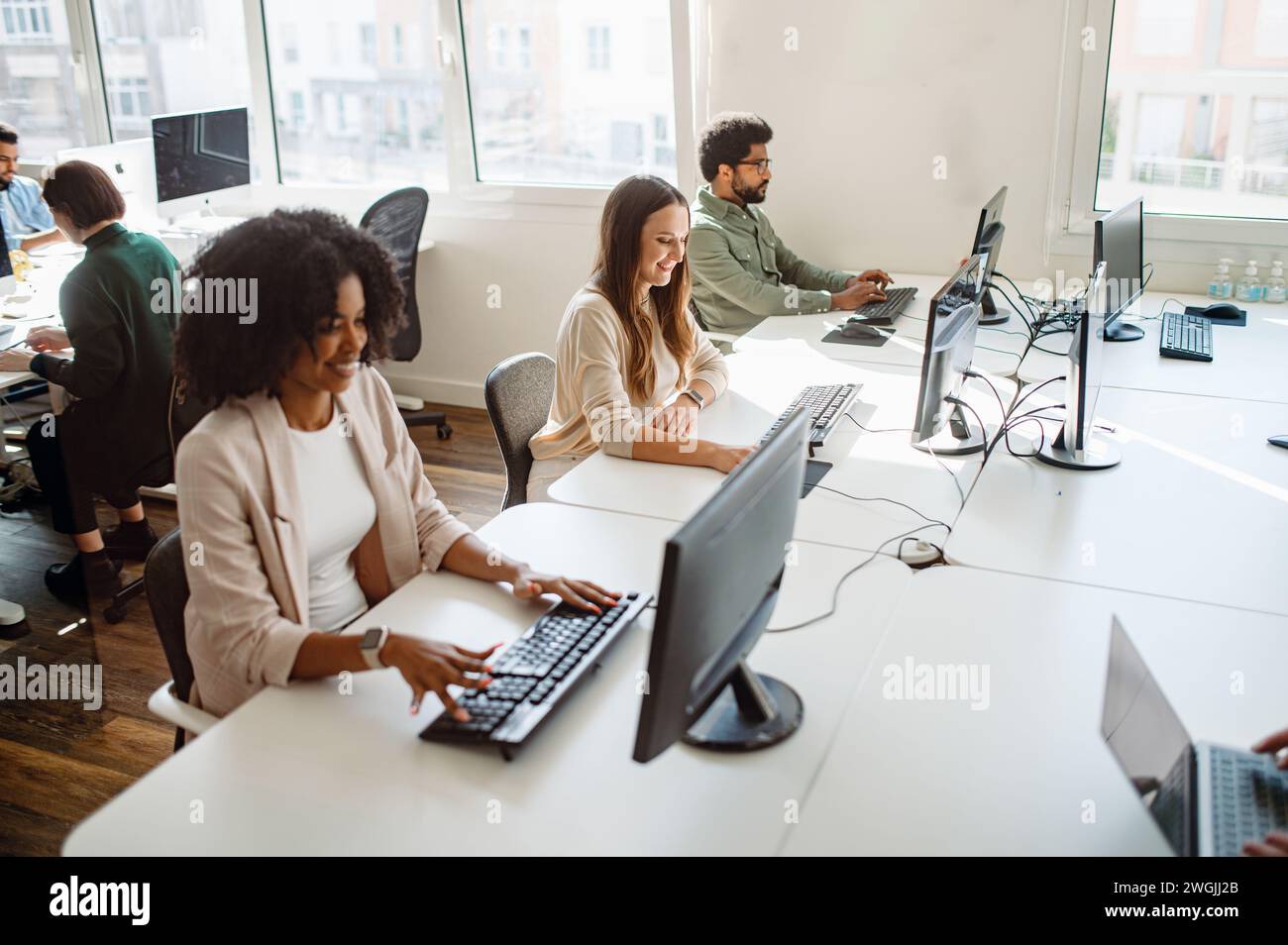 Dans un environnement de co-working spacieux et bien éclairé, un groupe diversifié de jeunes professionnels sont engagés dans leurs tâches respectives sur les ordinateurs, créant une atmosphère de productivité concentrée Banque D'Images