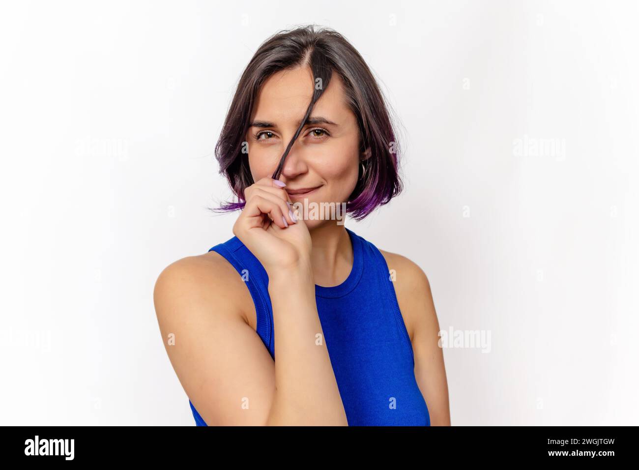 Femme joueuse, tenant flirtement la boucle, plissant devant la caméra dans le studio. Cheveux violets. Banque D'Images