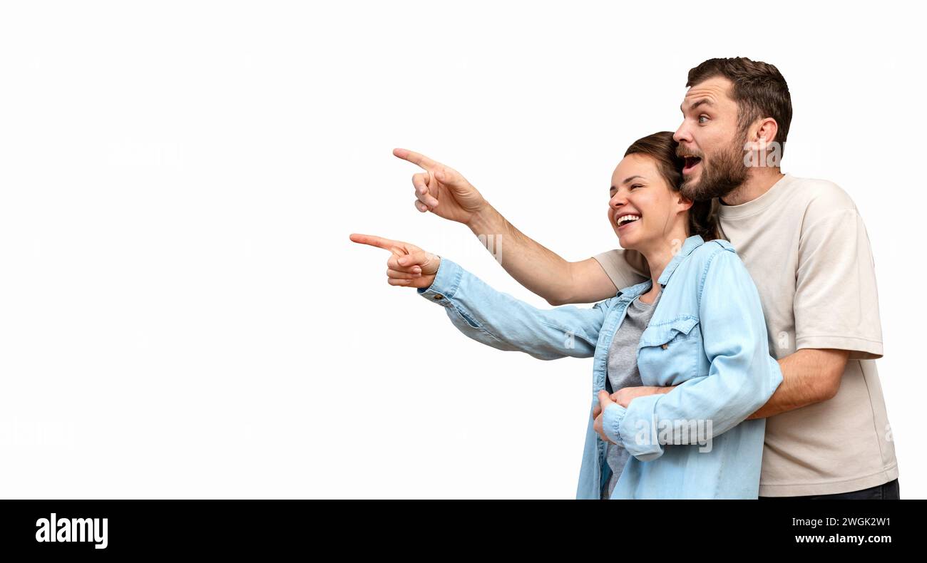 Couple hétérosexuel heureux isolé pointant du doigt sur un produit promotionnel. Banque D'Images