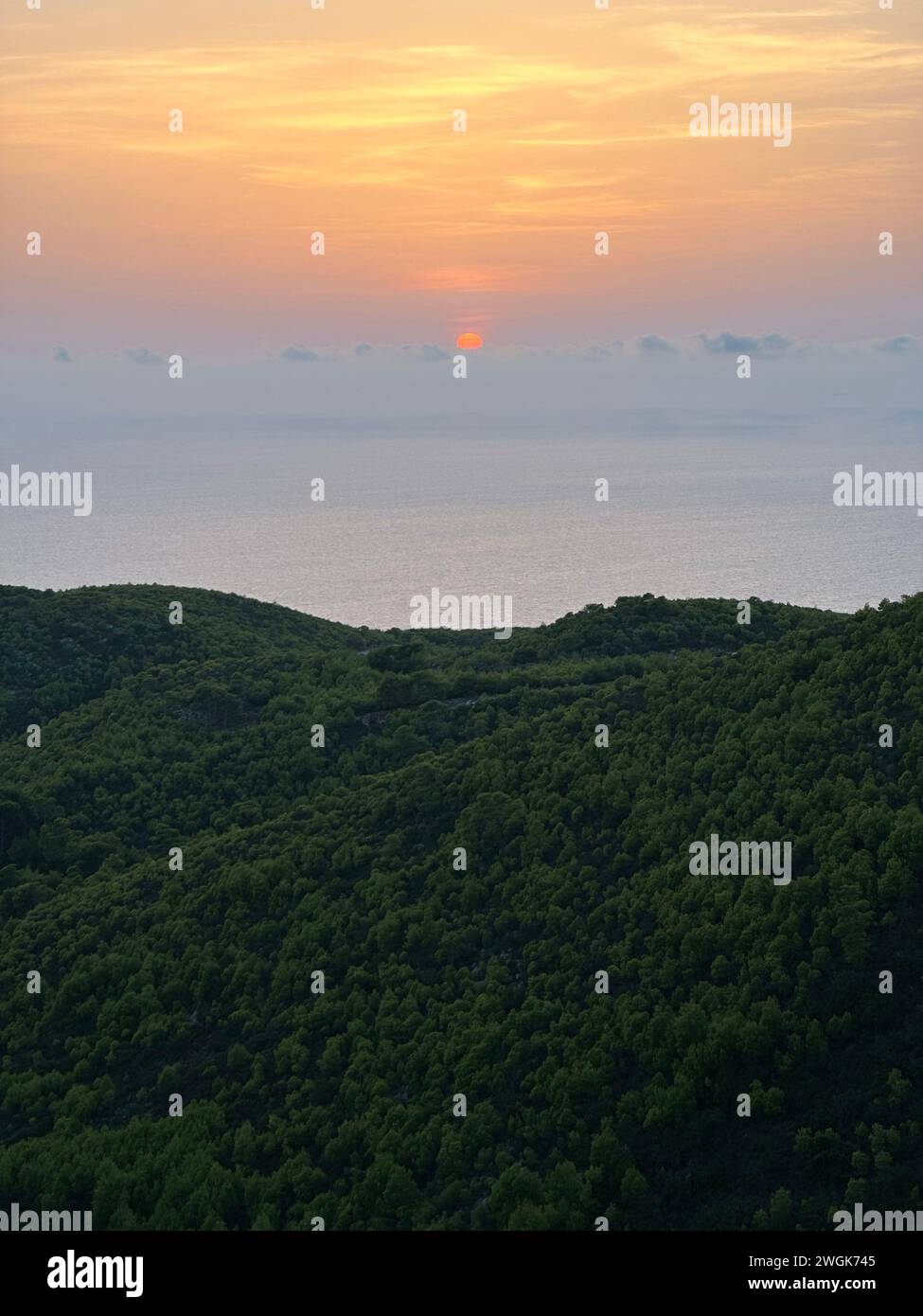 Coucher de soleil pins, oliveraies et vue sur la mer sur une île grecque. Coucher de soleil méditerranéen depuis le point de vue d'Agalas. Assis et regardant le coucher du soleil à Zakynth Banque D'Images