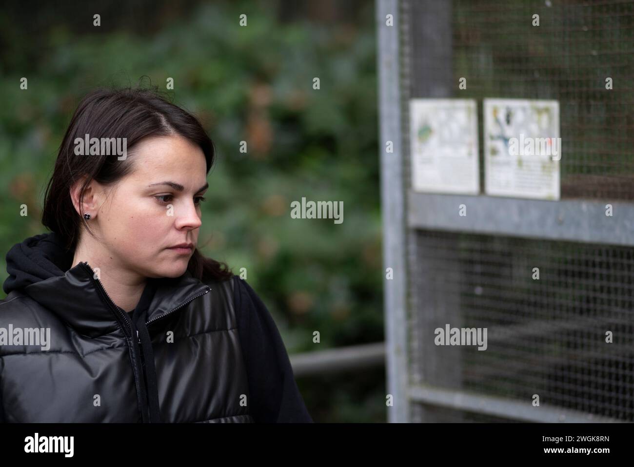 Jeune femme en veste noire regardant la caméra dans un parc. Banque D'Images