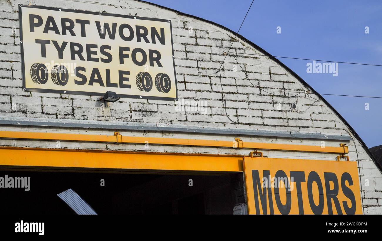 Barry, Vale of Glamorgan, pays de Galles 02 février 2024 : vente et montage de pneus annoncés dans une unité industrielle vintage voûtée sur un quai. Mur de briques blanches sale Banque D'Images