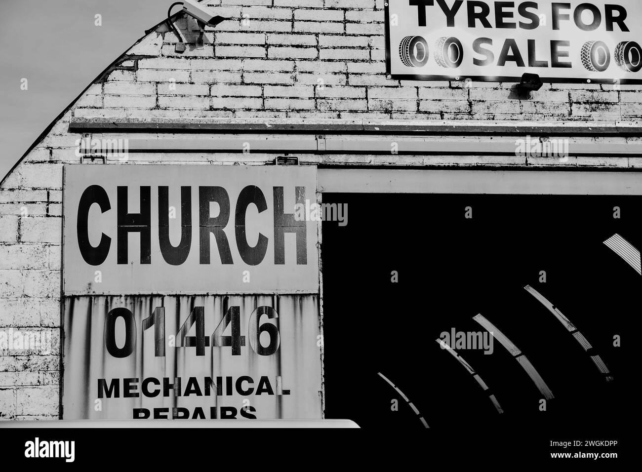 Barry, Vale of Glamorgan, pays de Galles 02 février 2024 : vente et montage de pneus annoncés dans une unité industrielle vintage voûtée sur un quai. Mur de briques blanches sale Banque D'Images