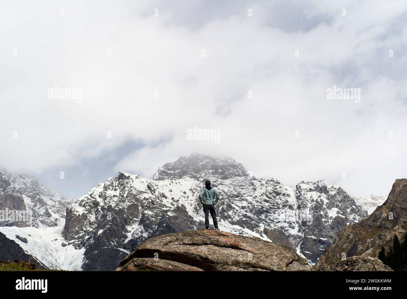 Vue arrière d'homme asiatique voyageur masculin debout au sommet d'un rocher regardant une montagne de neige dans le Xinjiang, en Chine Banque D'Images