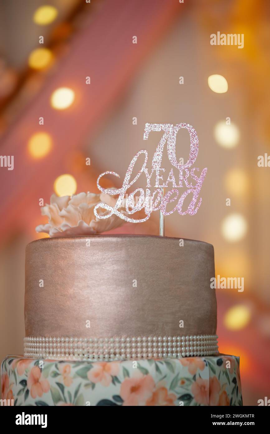 Soixante-dix ans anniversaire célébration gâteau d'anniversaire simples fleurs de pêche fermer beau fond chaudement éclairé Banque D'Images