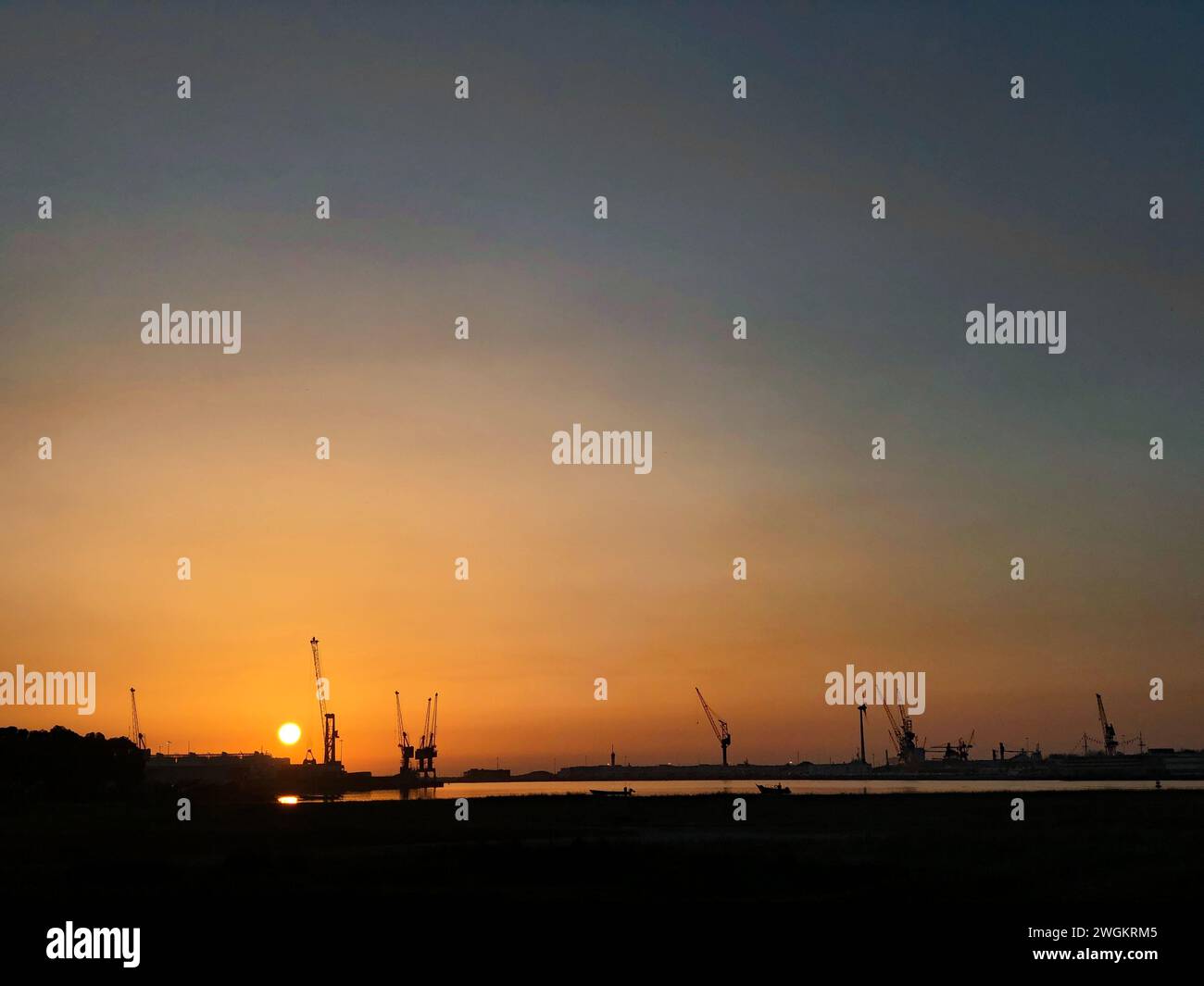 Viana do castelo, Portugal - 31 janvier 2024 : coucher de soleil sur le port maritime de Viana do Castelo avec les silhouettes des grues contre le ciel coloré Banque D'Images