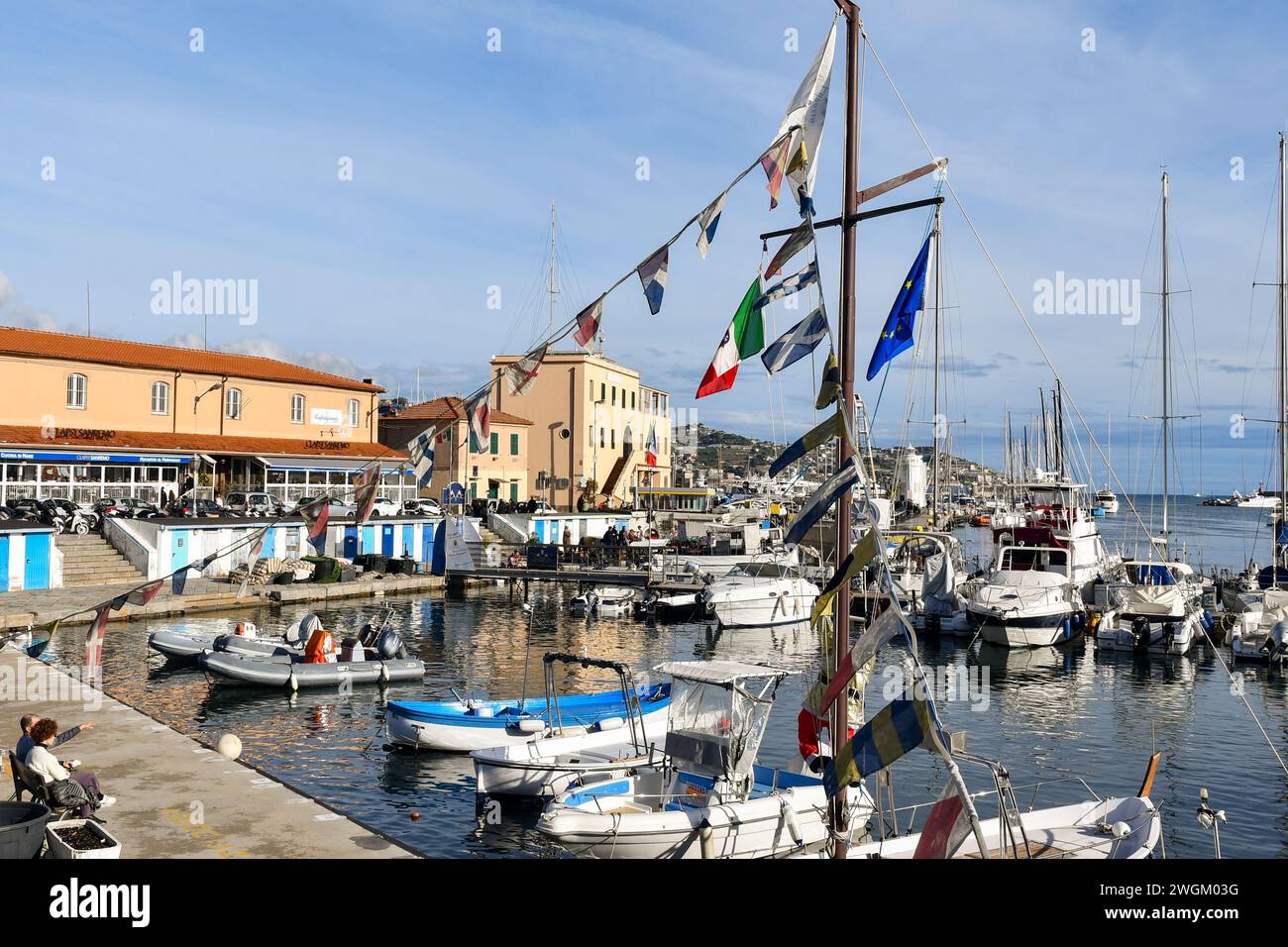 Vue en grand angle du Vieux Port avec des bateaux de pêche amarrés aux quais et de petits drapeaux des pays européens au premier plan, Sanremo, Italie Banque D'Images