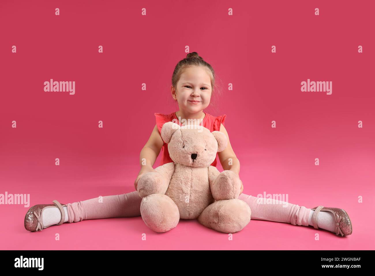 Jolie petite fille avec ours en peluche sur fond rose Banque D'Images