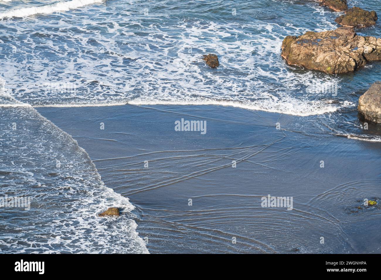 De petites vagues se brisent sur la belle plage de sable volcanique noir de Benijo. Playa de Benijo, Tenerife Banque D'Images