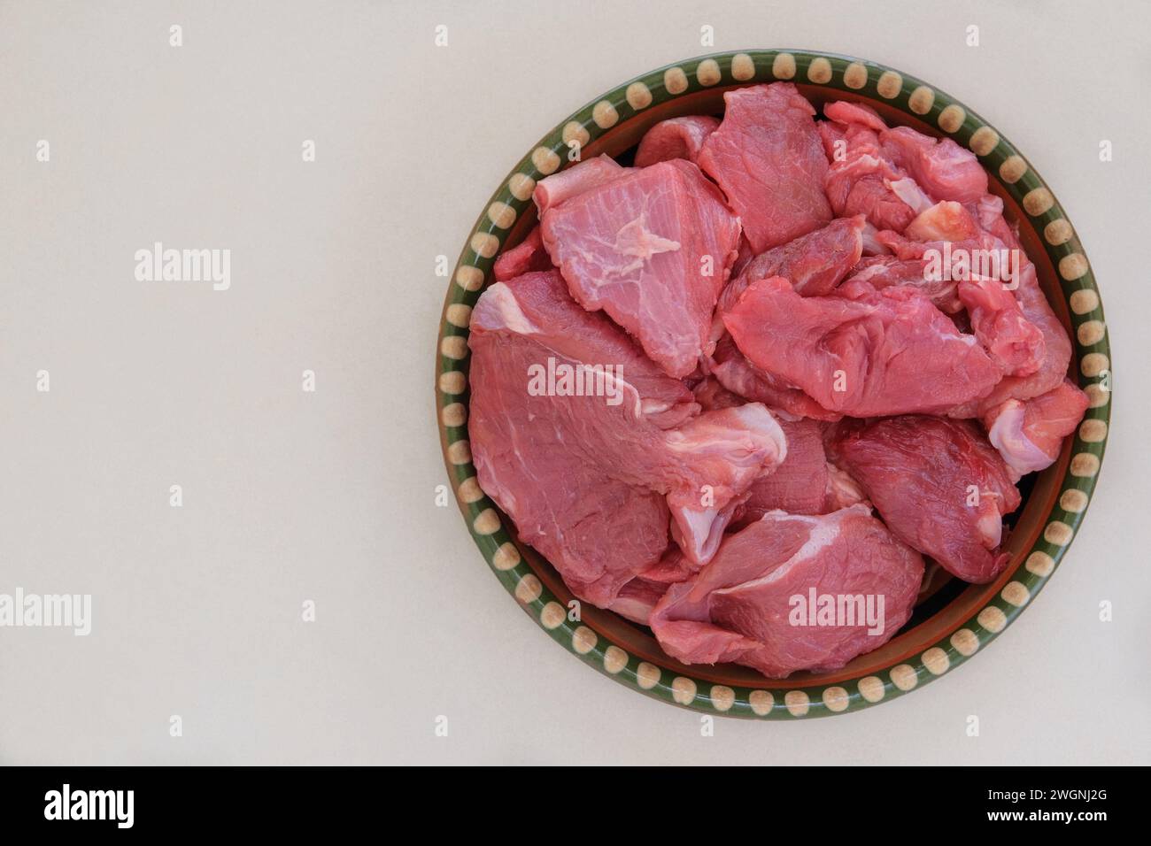 Morceaux de viande sur un plat rustique sur fond beige. Boeuf cru pour la cuisson. Vue de dessus. Banque D'Images