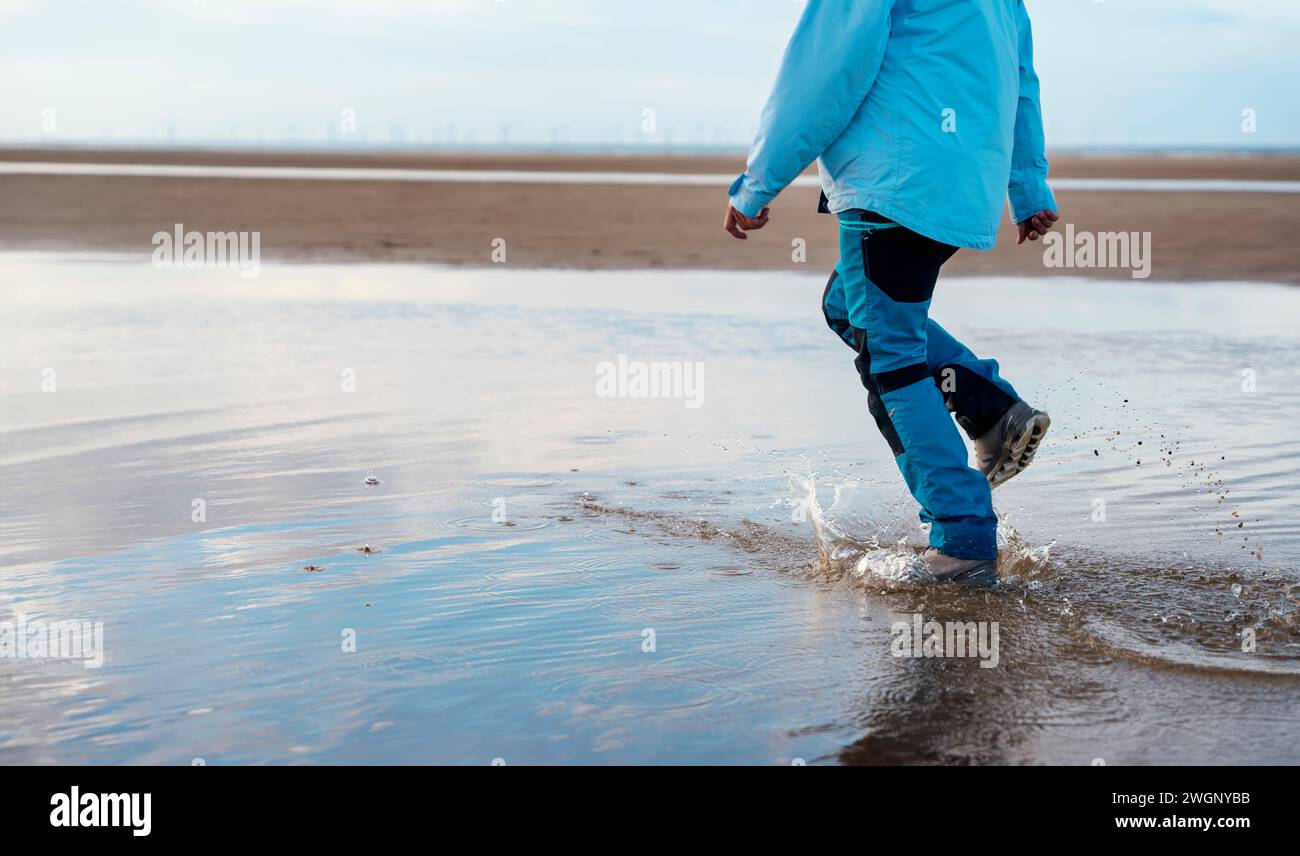femme en pantalon waterproove bleu et bottes courir sur la plage. Concept de style de vie de voyage Banque D'Images