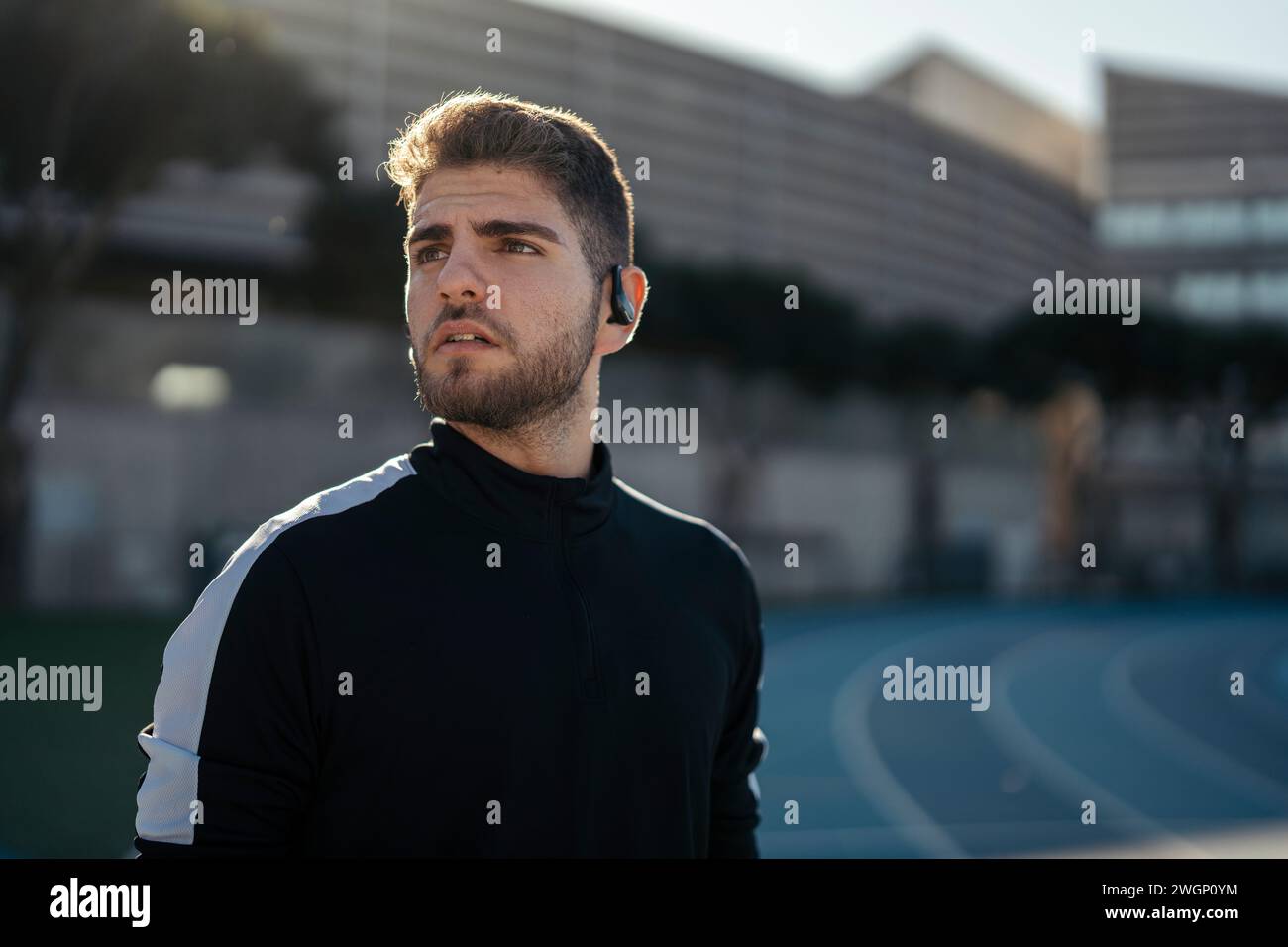 Un homme en chemise de sport noire debout sur la piste, regardant vers le haut Banque D'Images