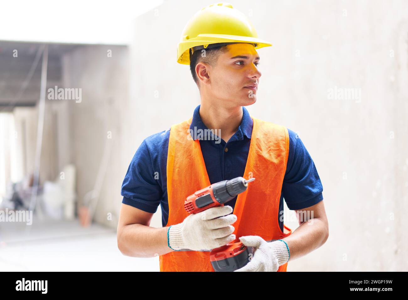 Outil électrique souriant tenant la main-d'œuvre de construction masculine Banque D'Images