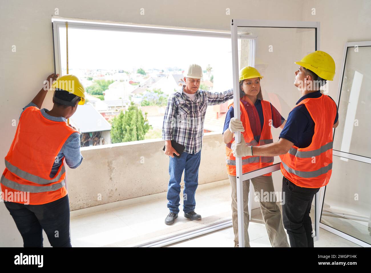 Superviseur principal près de collègues installant la fenêtre Banque D'Images