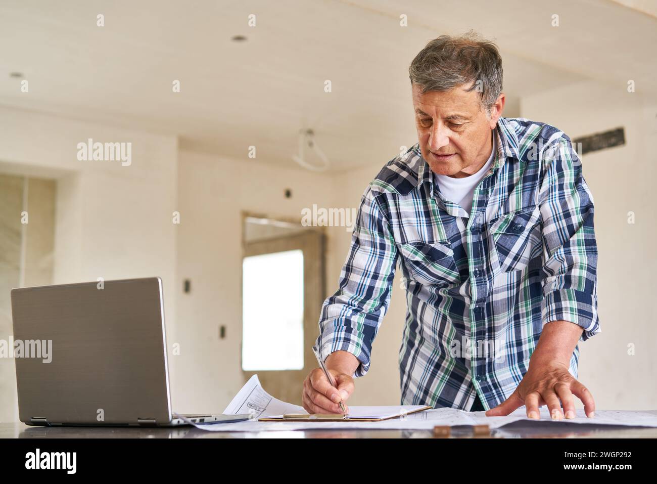 Architecte senior écrivant sur le presse-papiers au-dessus du plan Banque D'Images