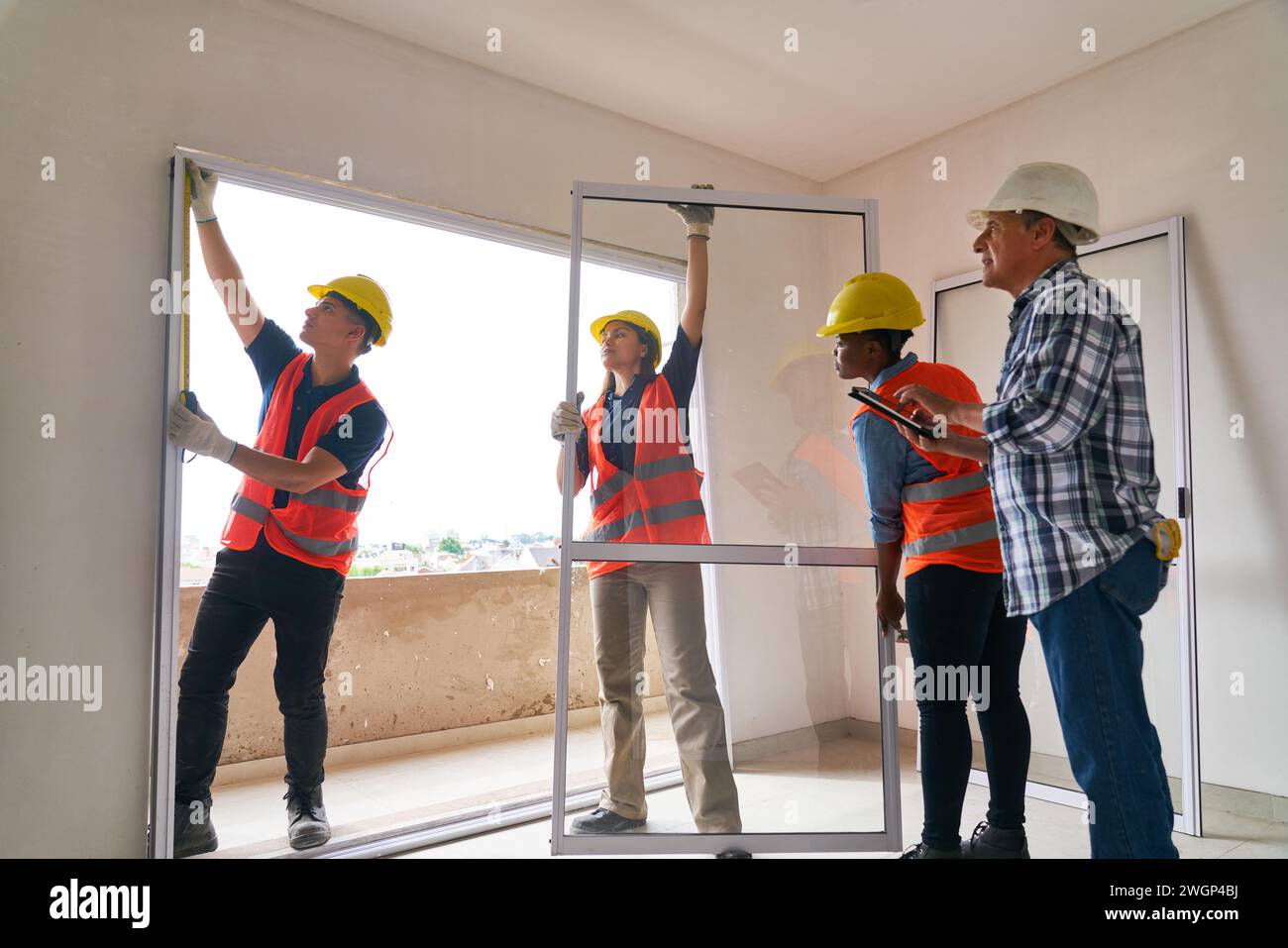 Superviseur principal près de collègues installant la fenêtre Banque D'Images