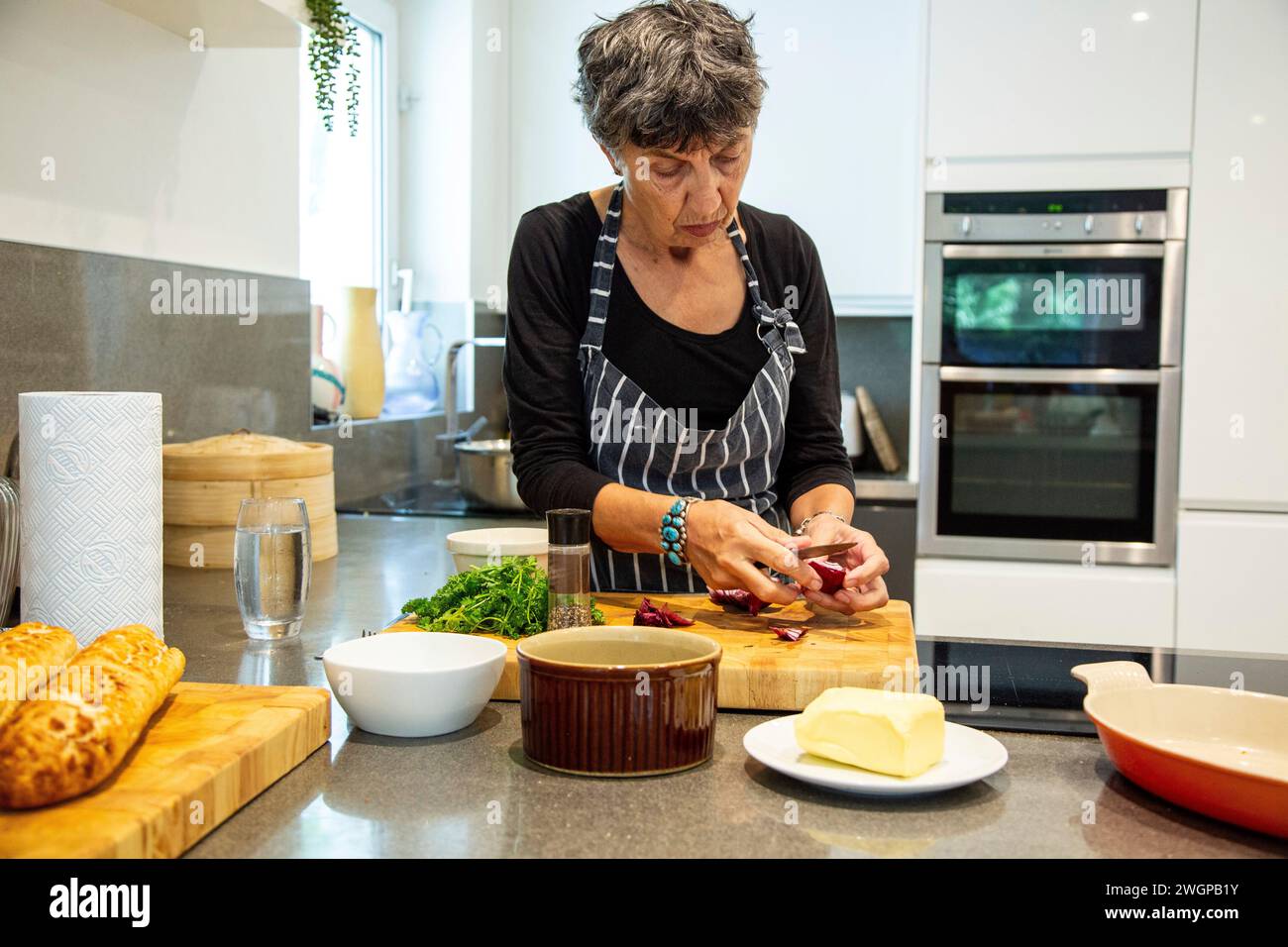 Une femme prépare la nourriture dans sa cuisine moderne Banque D'Images