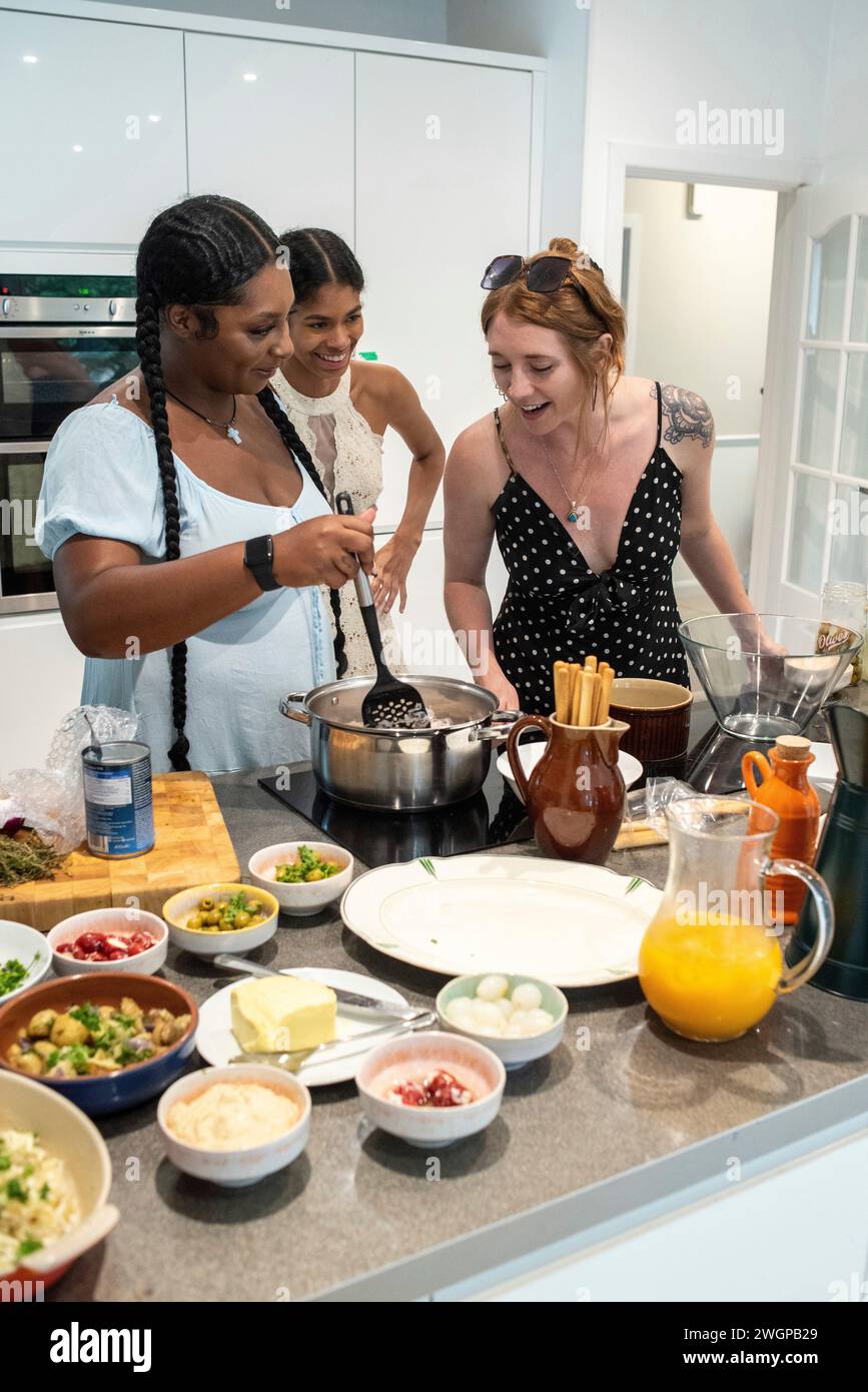 Un groupe mixte d'amies préparant des repas de fête dans une cuisine moderne Banque D'Images