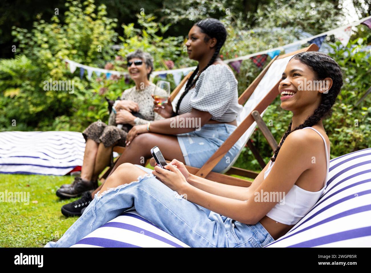 Groupe mixte d'amis féminins et de réunion de famille pour s'amuser et profiter d'une fête de jardin barbecue d'été. Banque D'Images