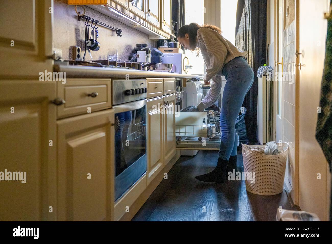 Belle femme nettoyant la cuisine et nourrissant le lave-vaisselle Banque D'Images