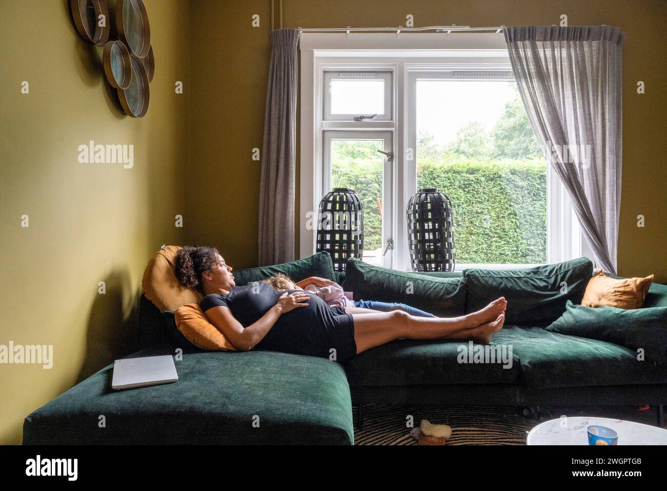 Mère enceinte assise se relaxant sur son canapé Banque D'Images