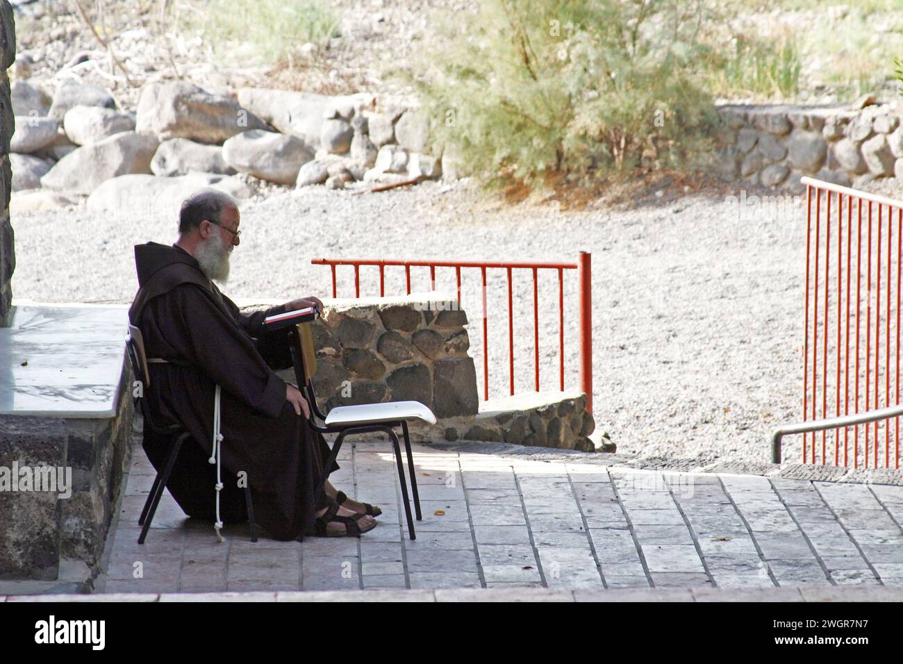 Un moine franciscain est assis devant l'église de la primauté de Saint Pierre, mer de Galilée, Tabgha, Israël Banque D'Images